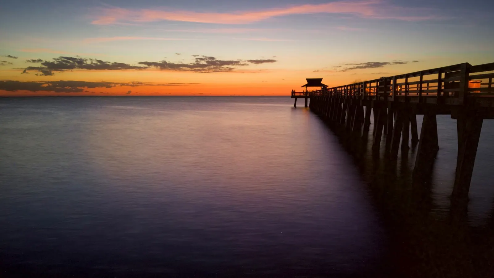 The Naples Pier at dusk over flat, calm water