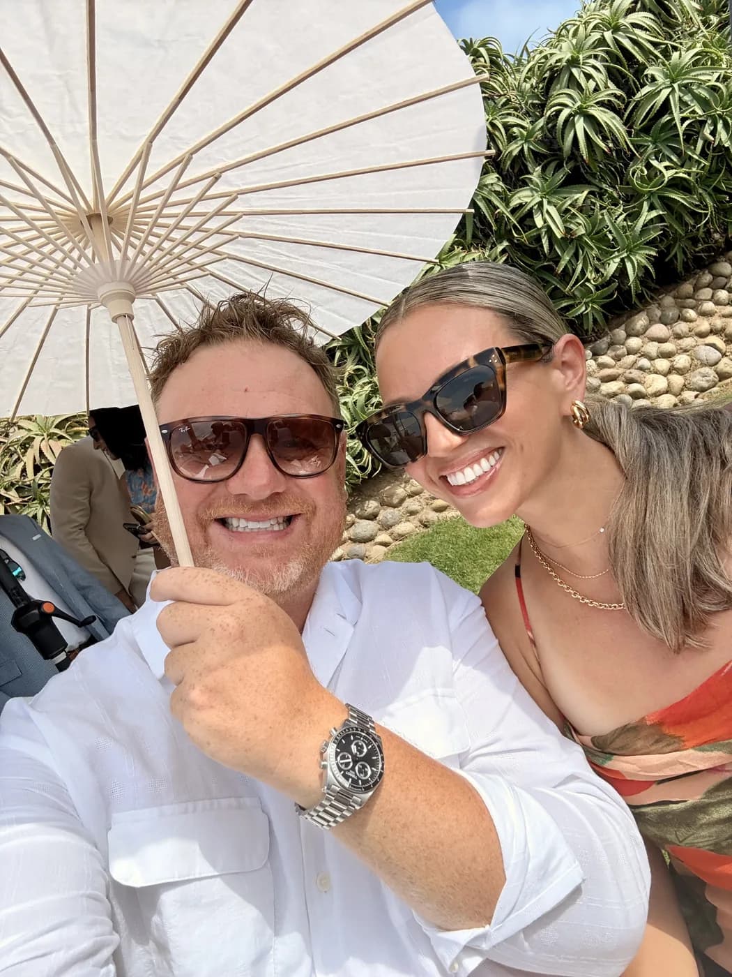 Nicole in sunglasses under a white paper parasol