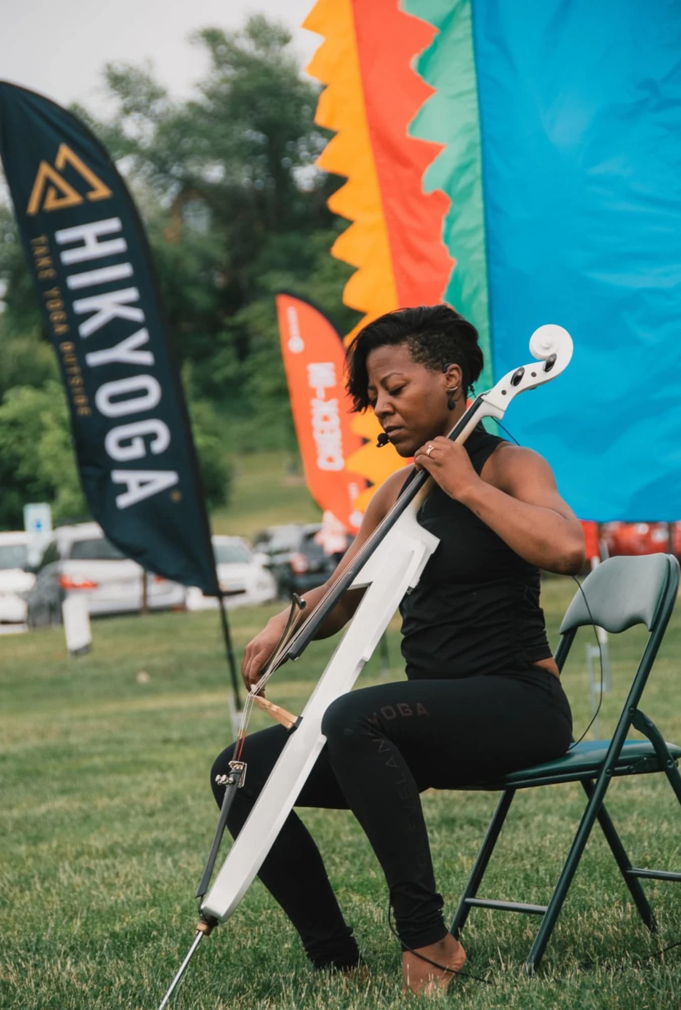 Cellist performing in front of a Hikyoga feather flag