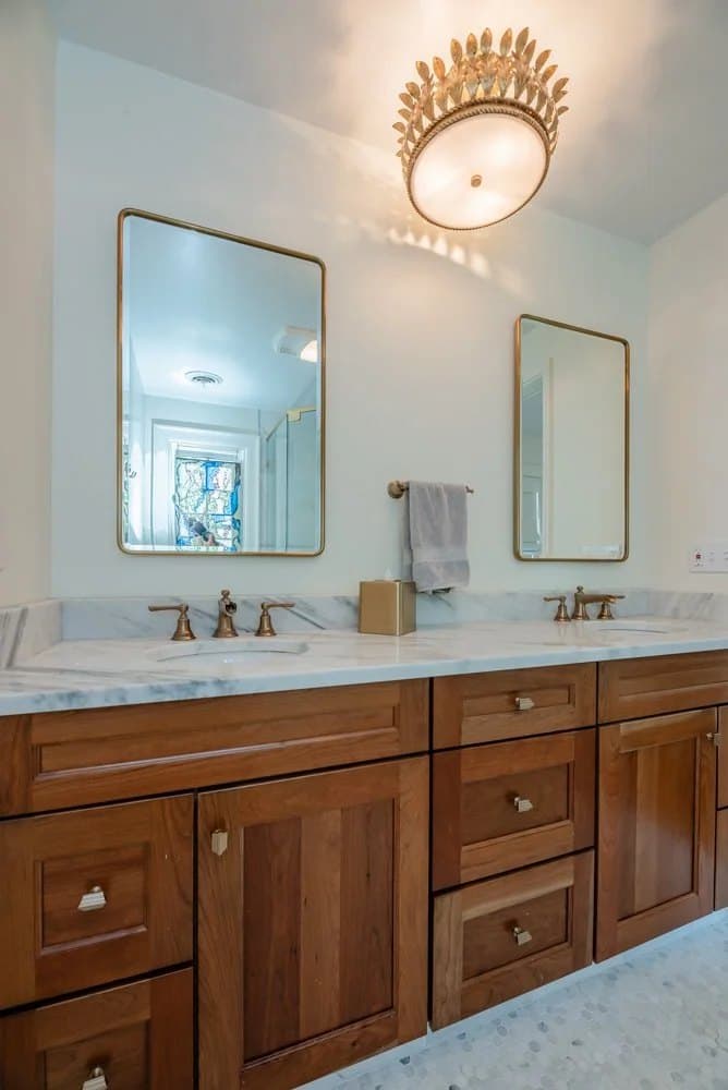Wood vanity with a gold-framed mirror and flush mount