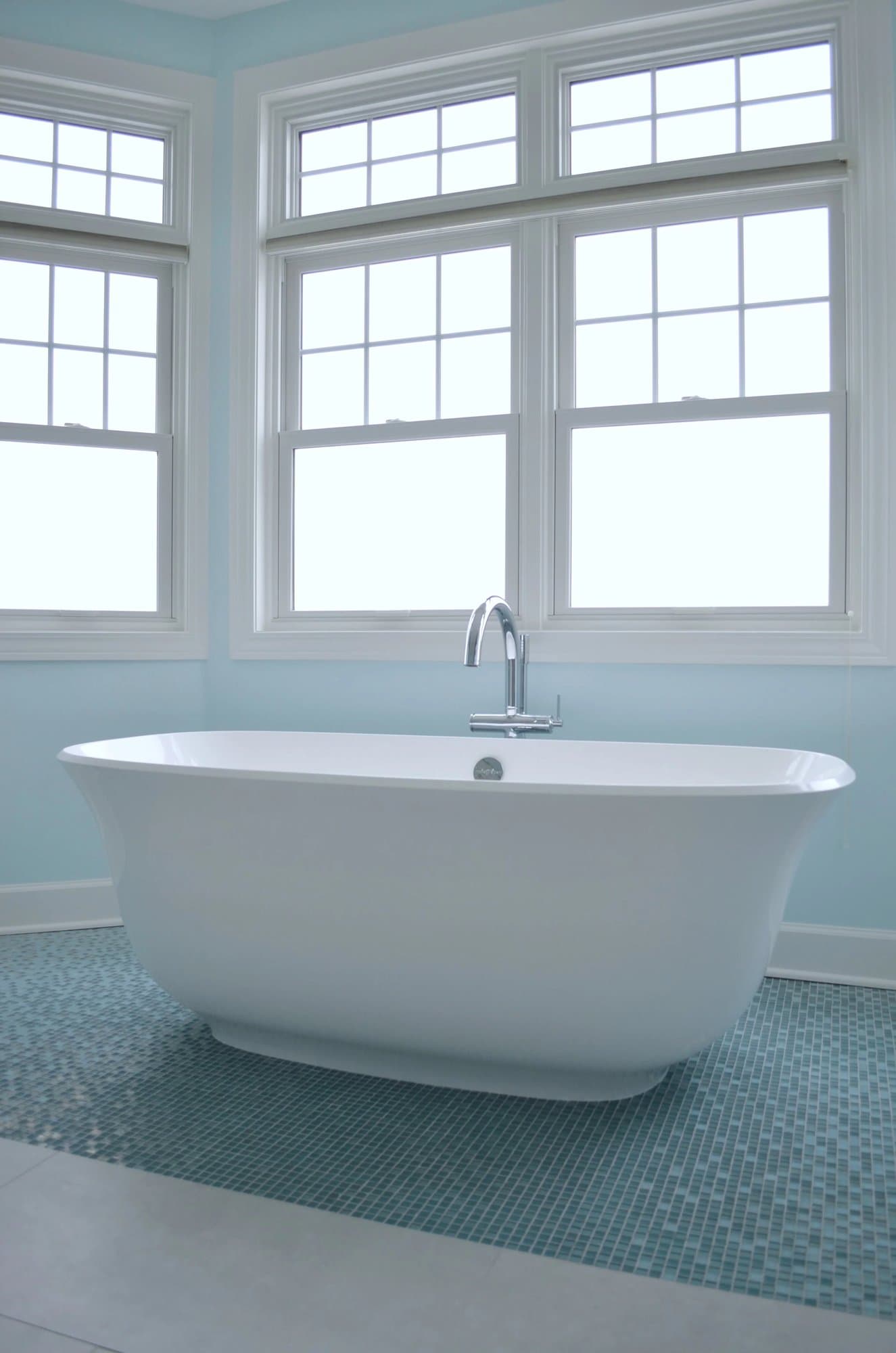 Freestanding soaking tub under a bank of windows